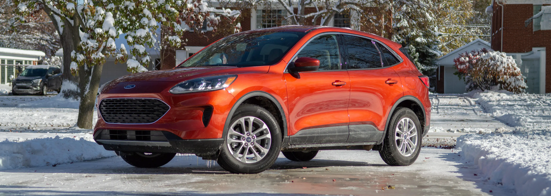 Un Ford Escape orange stationné dans une entrée résidentielle de Lanaudière l'hiver. Il est chaussé de pneus d'hiver